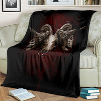 Black skull-and-wings blanket with red symbol across center, draped over cream chair.