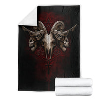 Black skull-and-wings blanket panel with red emblem, shown with folded white towels.