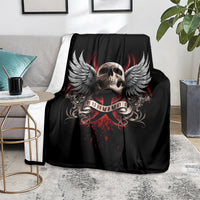 Black skull and wings graphic blanket with red accents, arranged on light carpet