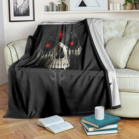 Black skull blanket with red-eyed skull and sword emblem, folded on striped sofa