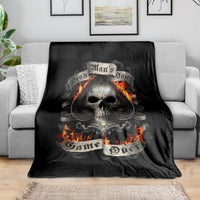 Black skull graphic blanket with flaming skull, draped over grey sofa