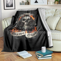 Black skull graphic blanket with flaming skull, draped across striped sofa