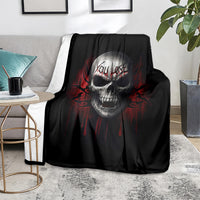 Black skull graphic fleece blanket draped over a sofa arm