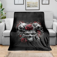 Black skull blanket spread on a sofa, featuring red roses and gray skulls