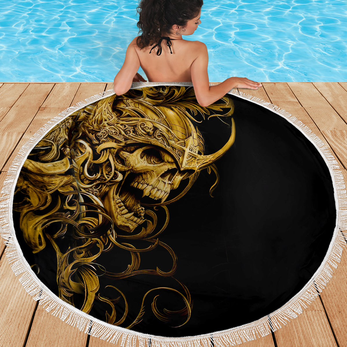 Round beach blanket with golden skull graphic on black and a white fringed border