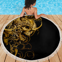 Round beach blanket with golden skull graphic on black and a white fringed border