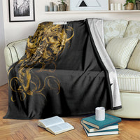 Black skull blanket with gold skull artwork, laid over sofa with throw edge