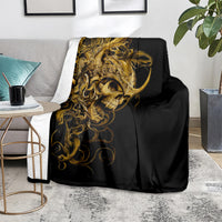 Black skull blanket with gold ornate skull, folded on couch seat