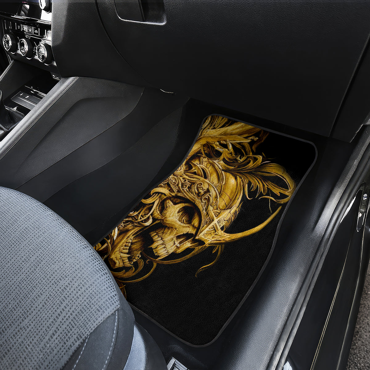 Black car floor mat with golden warrior skull graphic, placed in front seat area