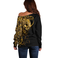 Black off-shoulder sweater showing gold skull graphic on back, long sleeves