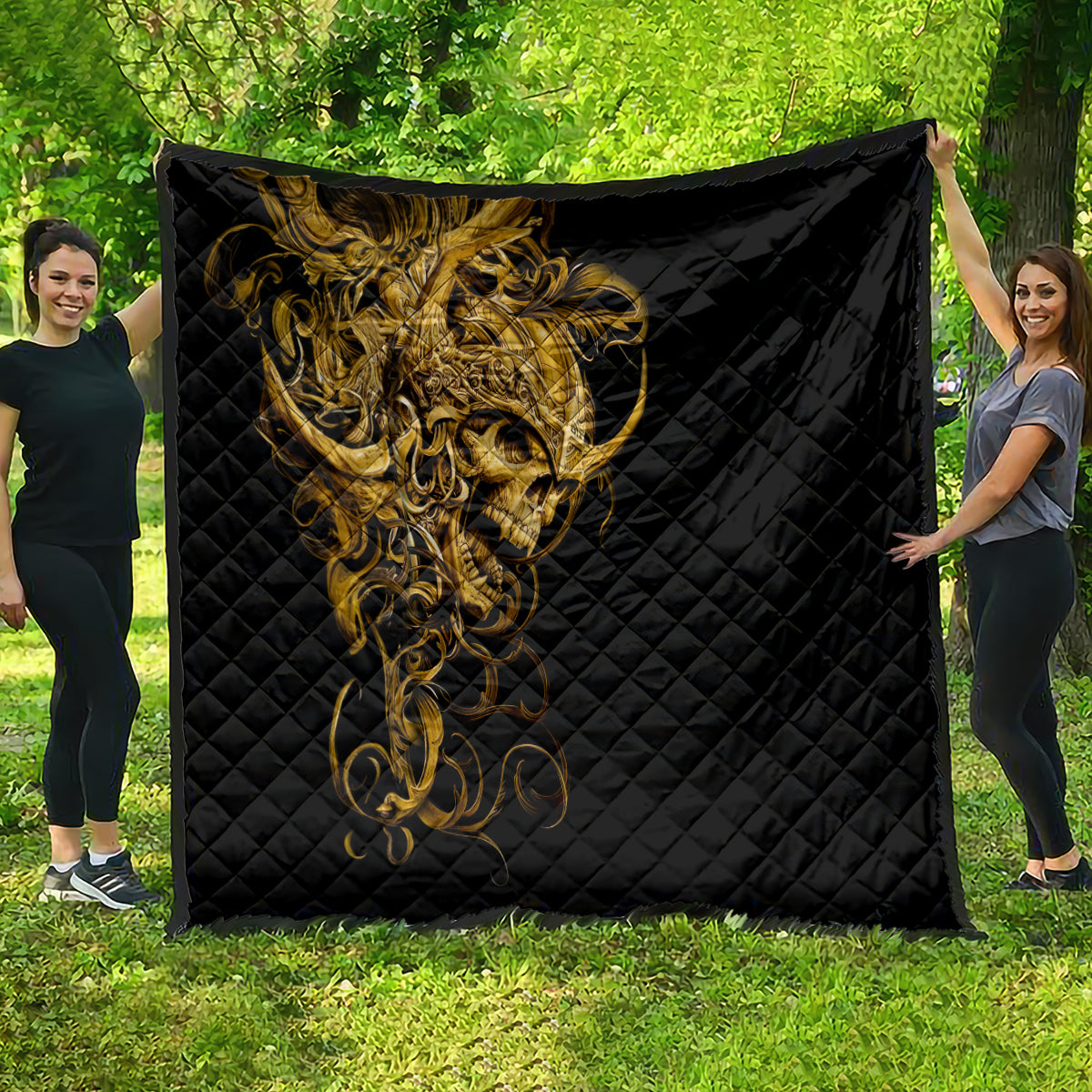 Black quilt with golden warrior skull design, spread out outdoors on grass