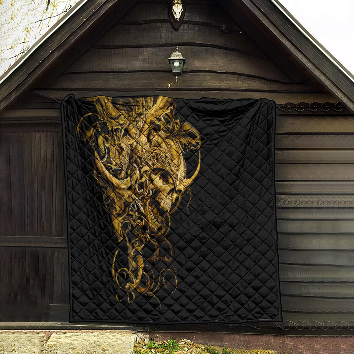 Black quilt with golden warrior skull print displayed in a wooden doorway