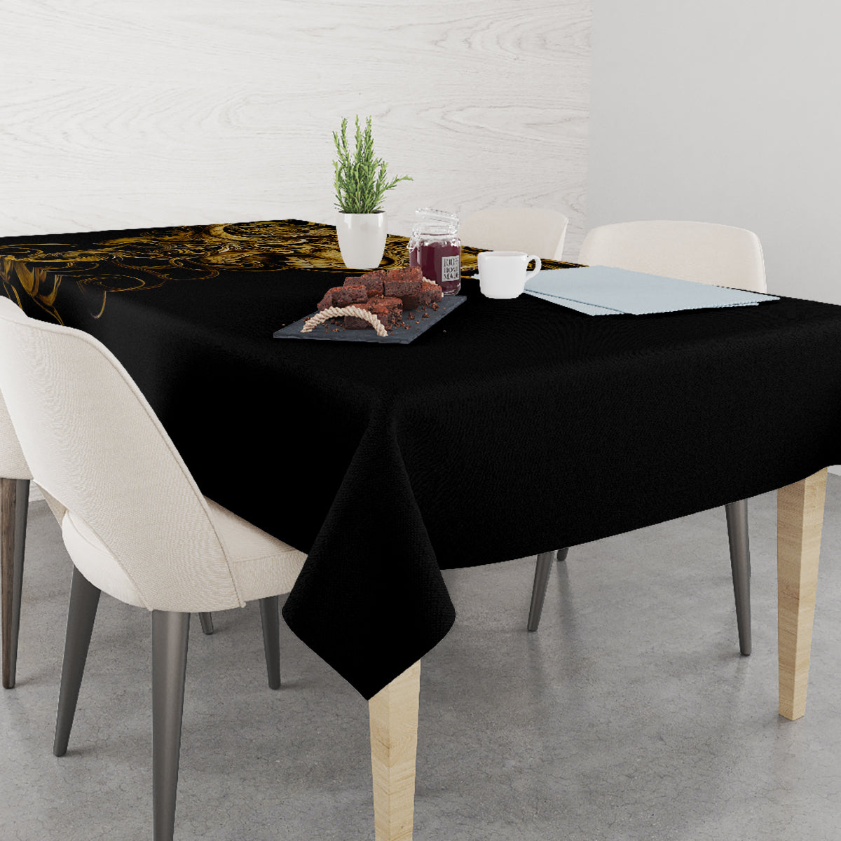 Black tablecloth with gold skull-and-warrior artwork on a dining table with tabletop items.