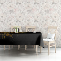Black tablecloth with gold skull-and-warrior print on a dining table against floral wallpaper.