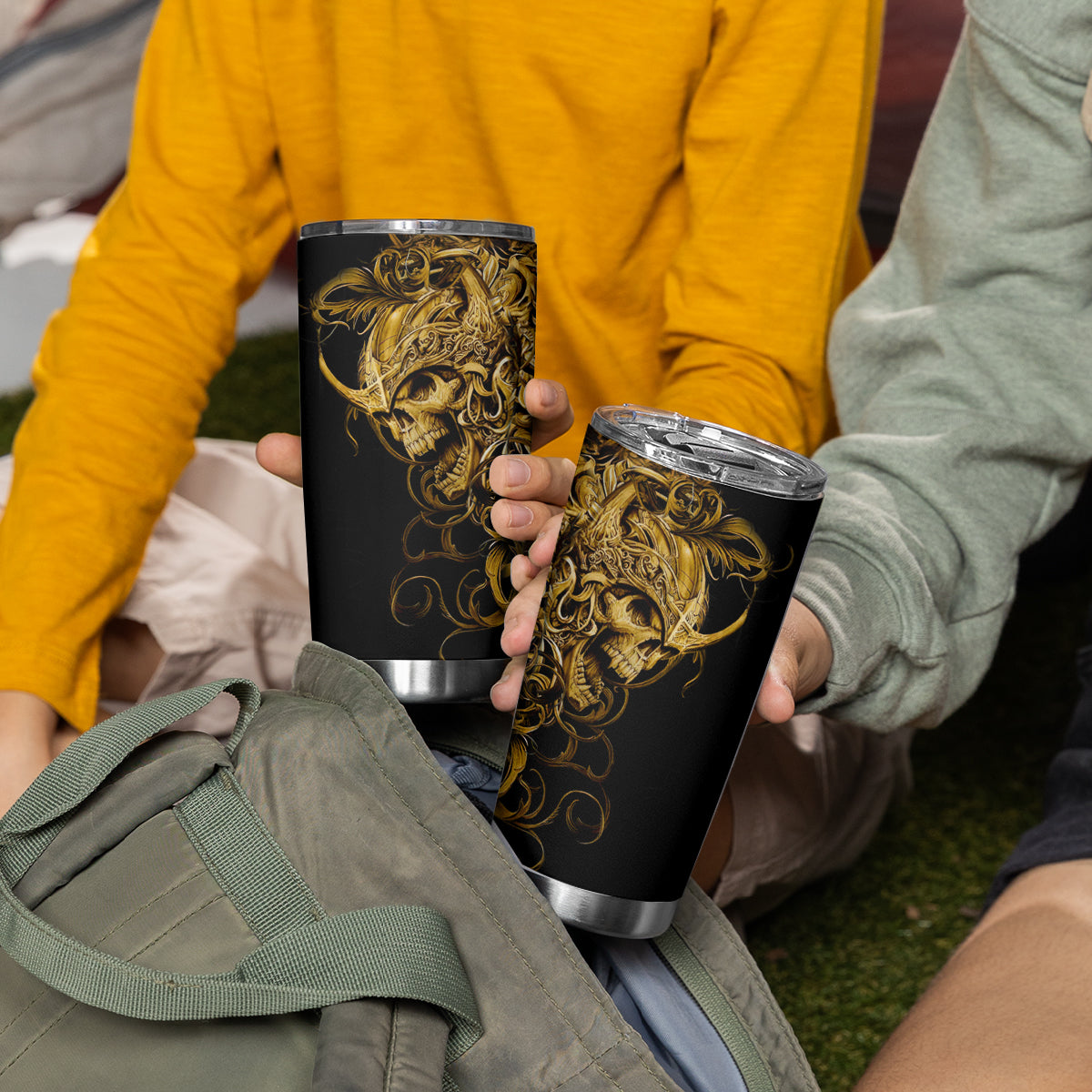 Black tumbler cup with gold skull warrior design in hands, clear screw-top lid.