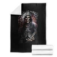 Black grim reaper skull blanket shown folded with stacked white towels, ornate crown graphic