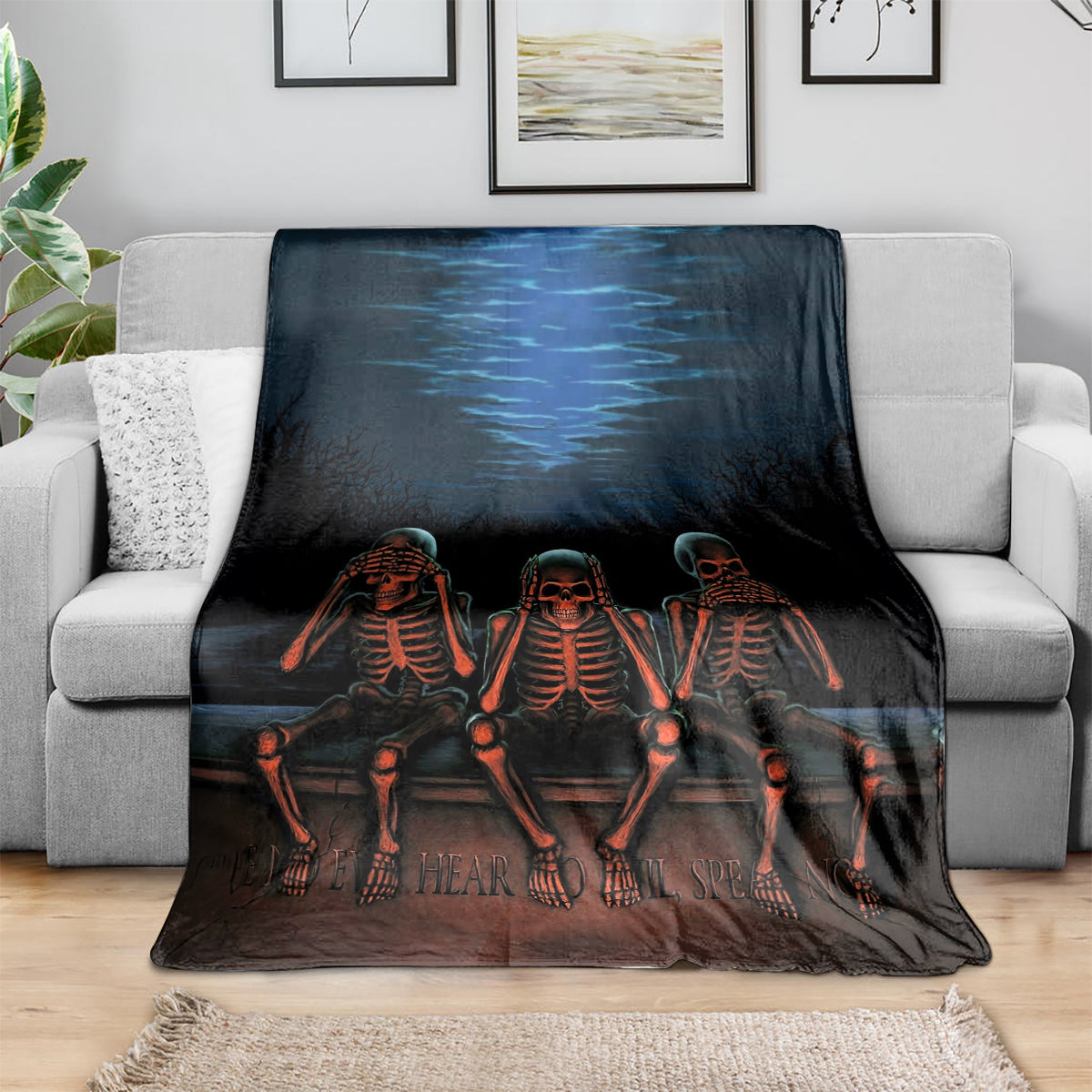 Black skeleton throw blanket draped over sofa with three orange skeletons