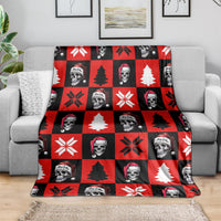 Red check Christmas blanket on sofa, featuring skeleton faces, pine trees, and snowflakes