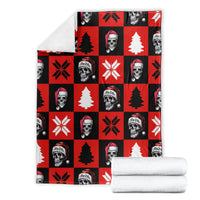 Red and black Christmas blanket with stacked pattern of skeleton faces, trees, and snowflakes