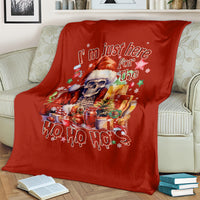 Red Christmas blanket with skeleton Santa graphic and 'Ho Ho Ho' lettering, on couch