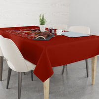 Red holiday tablecloth with printed holiday scene on a dining table surface