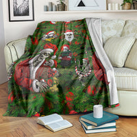 Green blanket draped over sofa showing multi skeleton Santa characters and red accents.