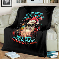 Black Christmas blanket with skeleton Santa graphic and quote text, on light bed
