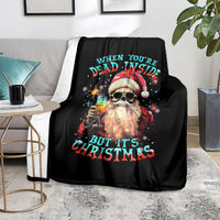 Black Christmas throw blanket with skeleton Santa graphic and colorful quote text on sofa
