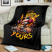 Black skull graphic blanket with roses and fiery lettering, draped on sofa