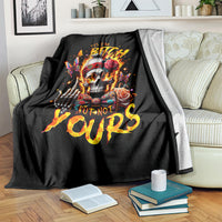 Black skull graphic blanket with roses and fiery text, draped over sofa