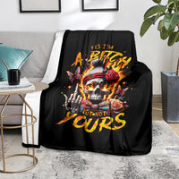 Black skull graphic blanket with roses and fiery lettering, on grey sofa