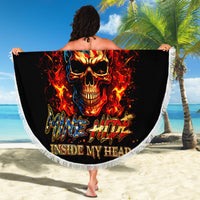 Black round beach blanket with white fringe, large fiery skull graphic held outdoors