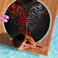 Round black beach blanket showing red devil skeleton and gray skull angel, white fringed edge