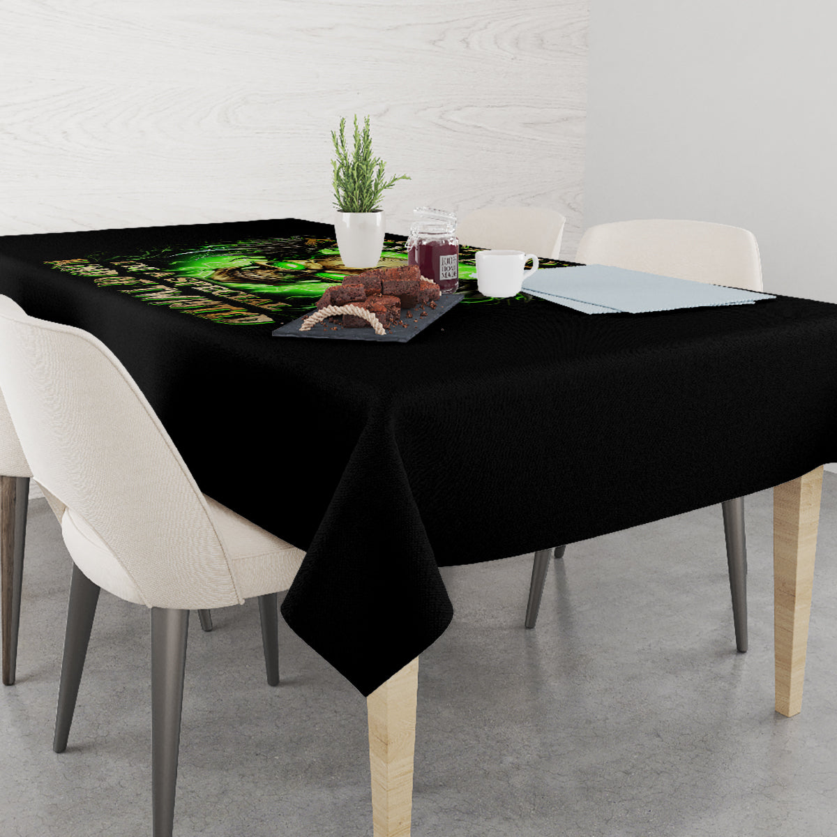 Black skull tablecloth with green skull print on dining table with chairs and dishes.