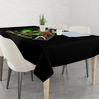 Black skull tablecloth with green skull print on dining table with chairs and dishes.