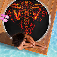 Round beach blanket with fiery skull design, shown from above, white fringed border