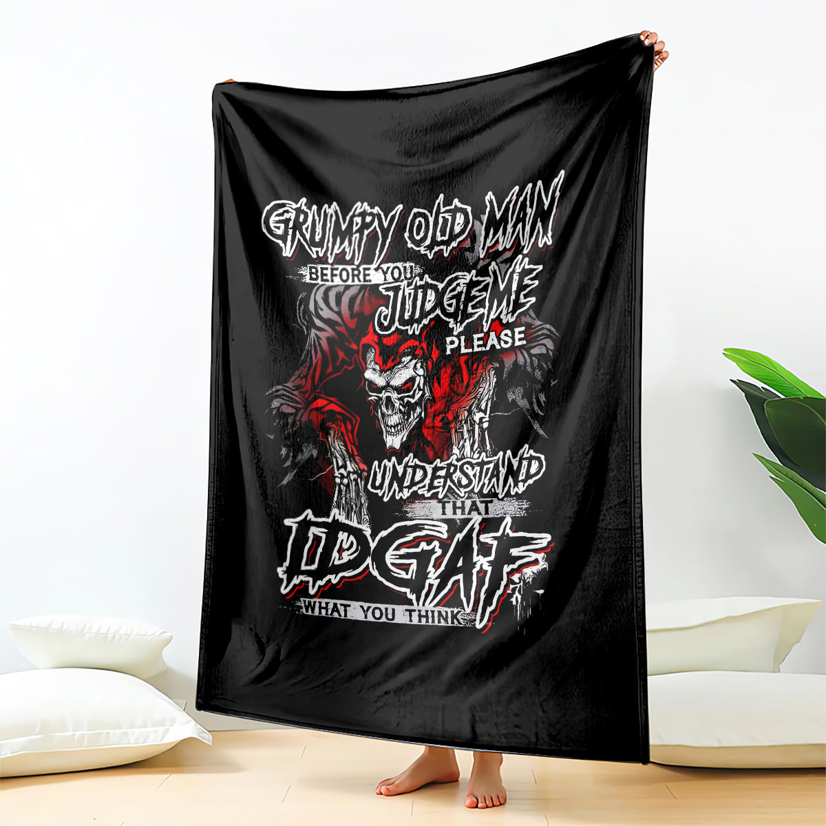 Black skull graphic blanket with red and white text, draped on person