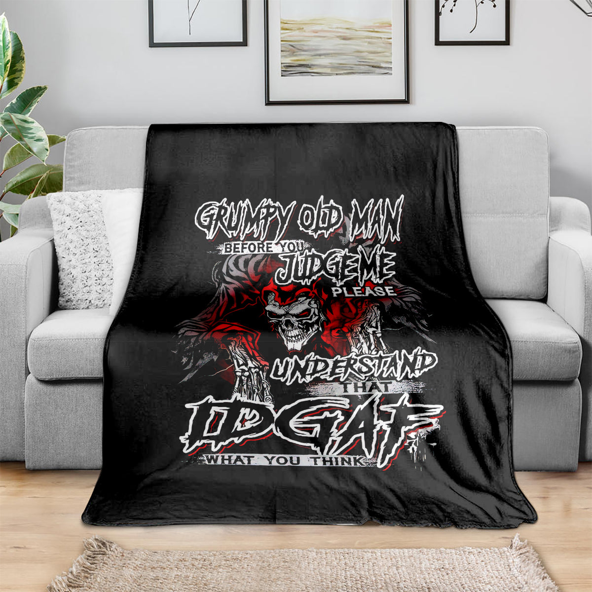 Black skull graphic blanket with red and white text, laid on sofa