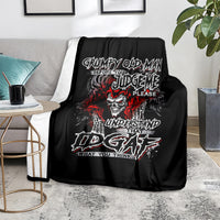 Black skull graphic blanket with red and white text, spread on gray couch