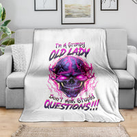 White skull graphic blanket on gray couch, featuring purple-pink skull and neon lettering