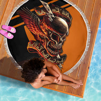 Circular beach blanket with winged skull flames artwork in black and orange, white fringe