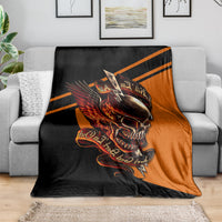 Black and orange skull with wings graphic blanket spread over a sofa