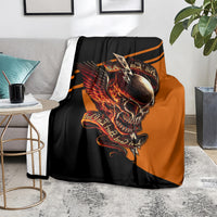 Black and orange skull with wings graphic blanket draped on a gray sofa