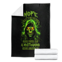 Black skull graphic blanket with neon green glowing face, flat view beside folded towels