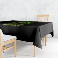 Black tablecloth with green skull graphic draped over wooden dining table corner.
