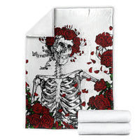 White skull and red rose blanket with stacked white folded towels beside it