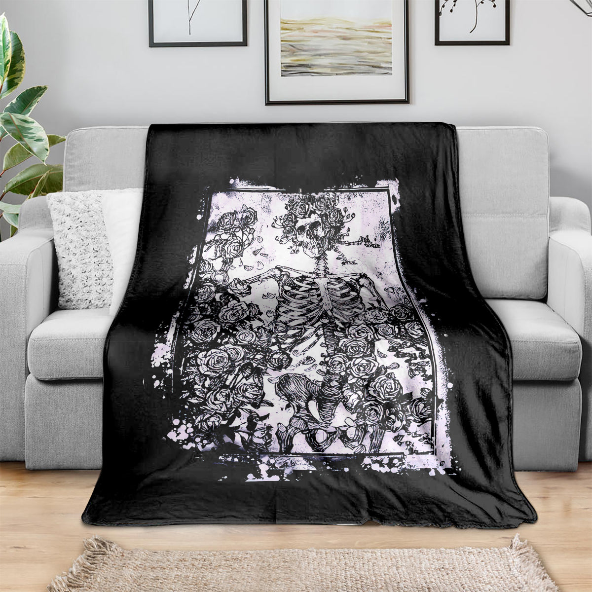 Black skull and rose throw blanket laid over a couch, white printed artwork