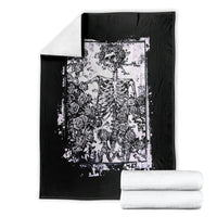 Black skull and rose graphic blanket with white framed print, folded with stacks