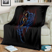 Black blanket with close blue-and-gold devil face skull artwork, draped on couch