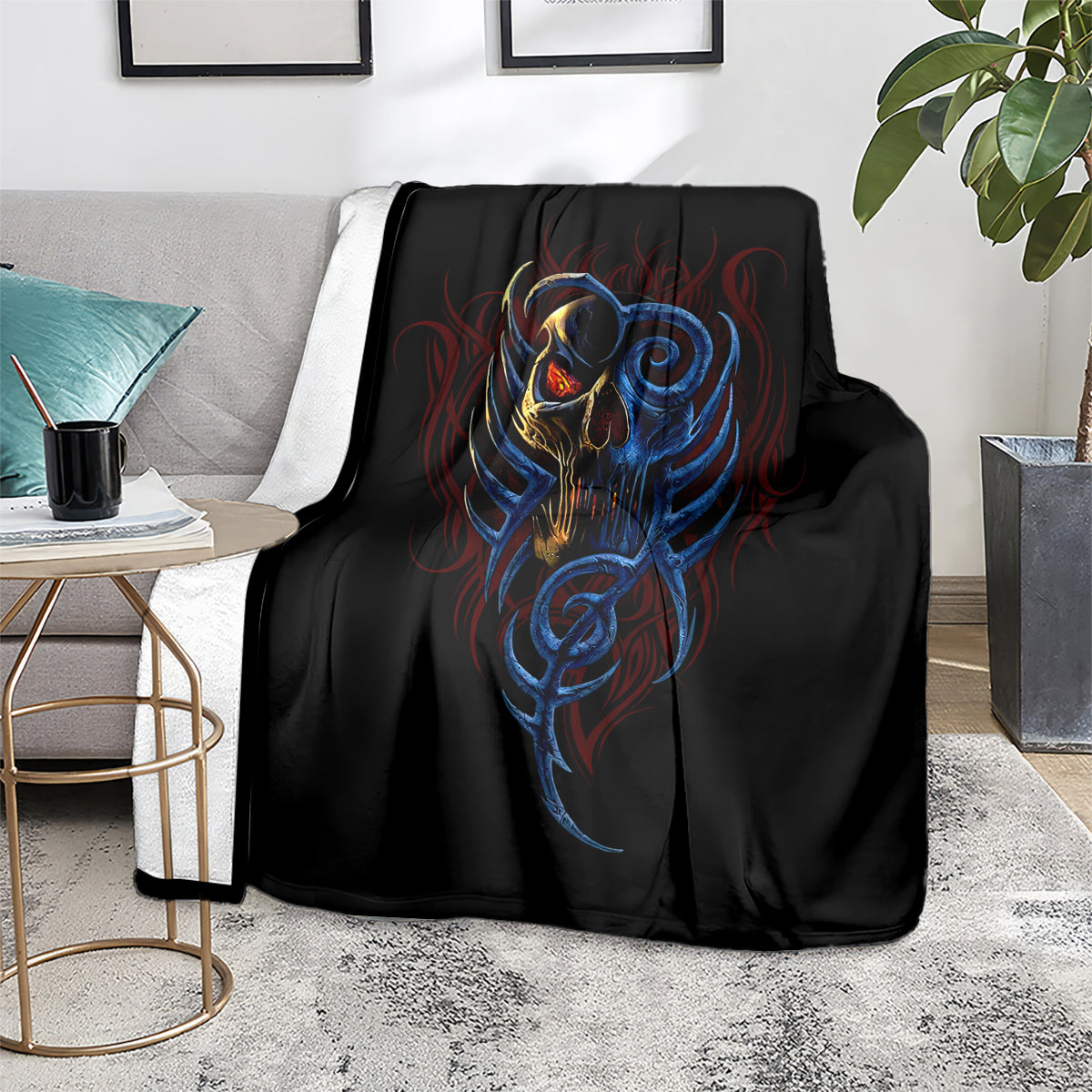 Black blanket with blue-and-gold devil skull graphic, placed on light gray sofa